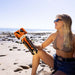 Woman sitting on a beach holding a CLIQ ClassiQ 2.0 folded chair
