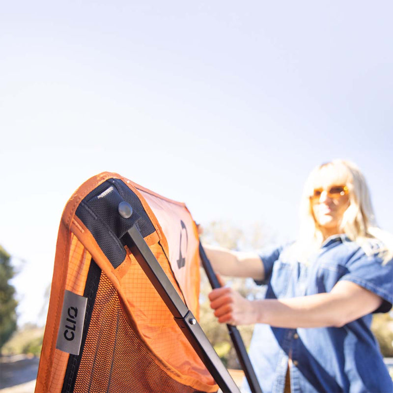 CLIQ ClassiQ 2.0 portable chair in burnt orange being opened by a person