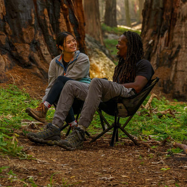 Two people in the woods seated on CLIQ ClassiQ 2.0 portable lightweight camping chairs