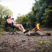 Man sitting in a CLIQ EpiQ Lounge chair by a campfire in a natural setting