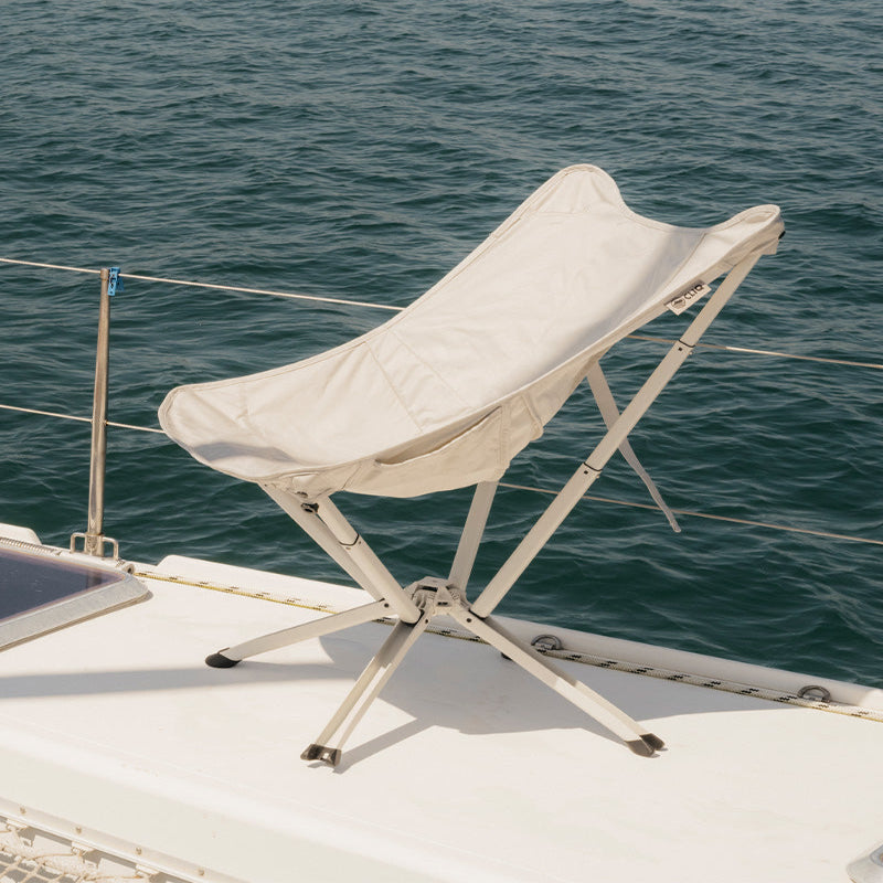 CLIQ Riviera foldable lounge chair in cloud white on a boat with ocean in the background