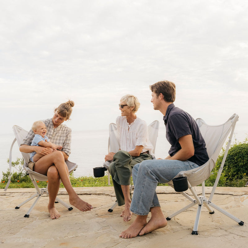 Three adults with a baby sitting in CLIQ Riviera Lounge chairs on a beach, intuitive design sets up in 15 seconds