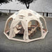 Coody Aurora Dome inflatable tent in beige with furniture inside, set up near a body of water.