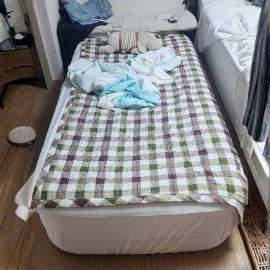Coody Inflatable air mattress with checkered blanket and clothes in a room setting
