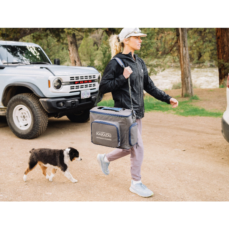 Woman carrying Kakadu Outback Shower Carry Bag, padded shoulder strap offers hands-free option for longer hauls