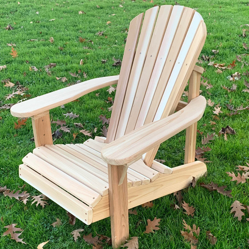 Wooden Adirondack chair on a grassy area with fallen leaves