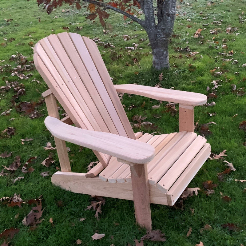 Wooden Adirondack chair on a grassy area with fallen leaves
