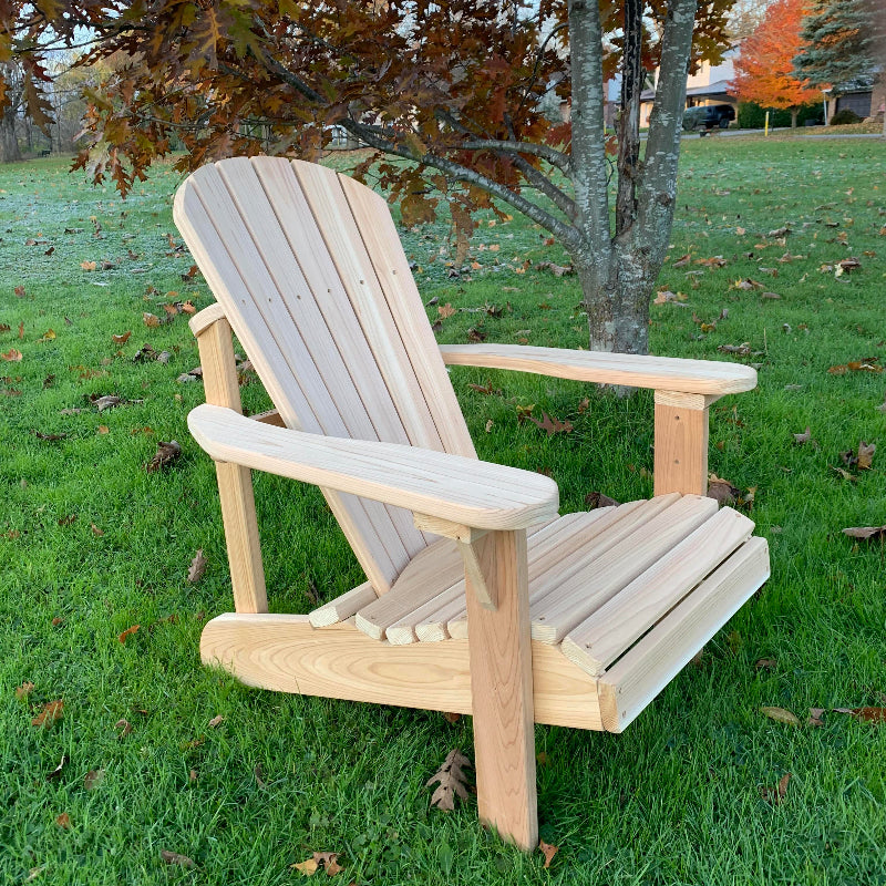Wooden Adirondack chair by The Best Adirondack Chair Company on a grassy area with trees in the background
